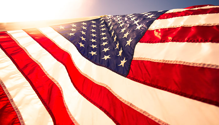 Photo of United States flag with sun shining above