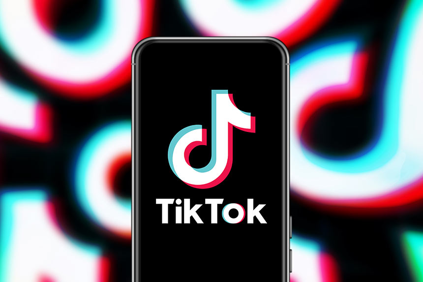 Graphic showing smart phone with TikTok logo on screen and blurry TikTok logo in background